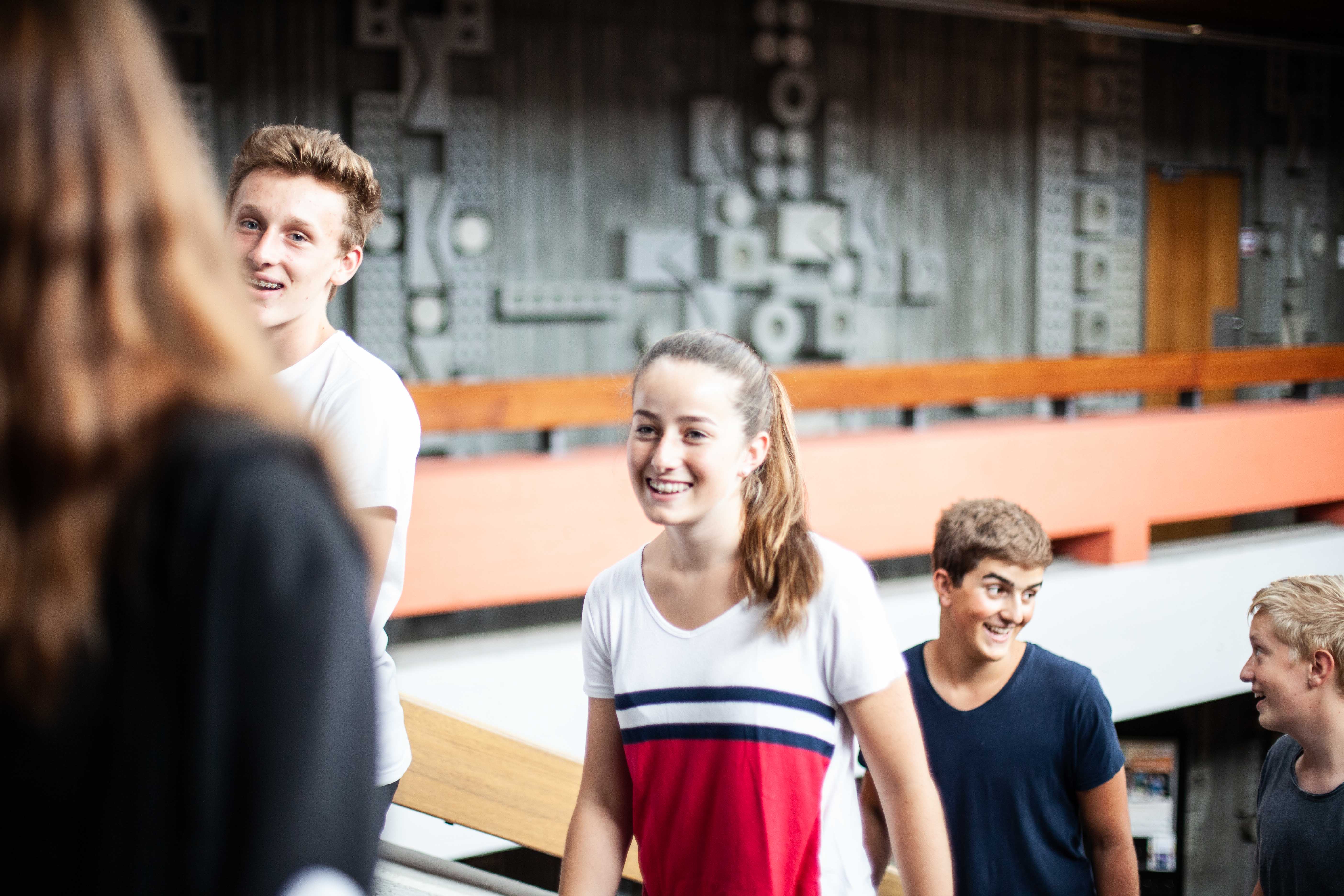 Schüler und eine Schülerin auf der Treppe im Schulgebäude